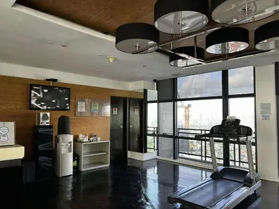 a gym with a treadmill in a room with a large window at Gramercy Makati Condotel in Manila