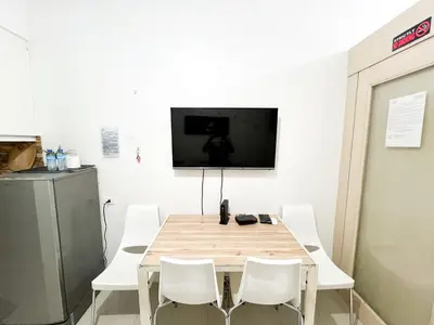 a table with white chairs and a tv on a wall at Sea Residences Navigators in Manila