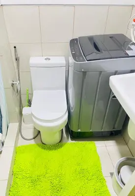 a bathroom with a toilet and a green rug at Cozy condotel Field Residence in Manila