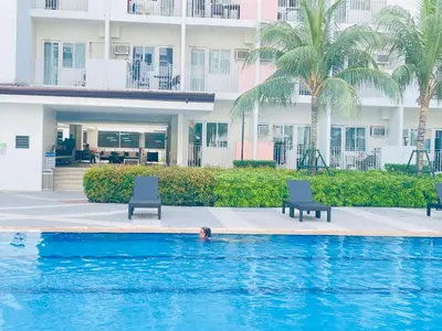 a person swimming in a pool with two chairs and a building at Cozy condotel Field Residence in Manila