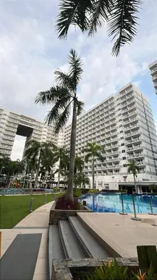 a palm tree in front of a large building at Shell Residences near MOA and NAIA by Mae in Manila