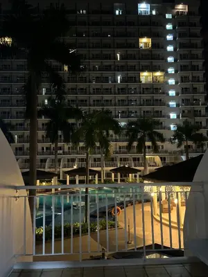 a large building with a swimming pool at night at Shell Residences near MOA and NAIA by Mae in Manila