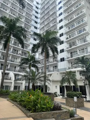a group of palm trees in front of a building at Shell Residences near MOA and NAIA by Mae in Manila