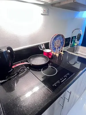 a kitchen stove with a frying pan and a sink at UNISTAY Coast Res R19 w Bal Sunset Vw Worldtrade in Manila