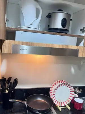 a kitchen with a stove with a frying pan and utensils at UNISTAY Shore 3 Pool View w Balcony near MOA in Manila