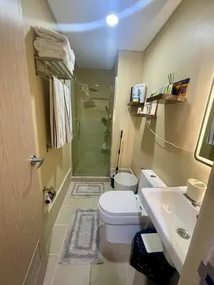 a bathroom with a shower and a toilet and a sink at Empirestatecation at Leaf Residences in Manila