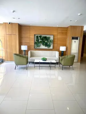 a living room with a white couch and two chairs at Empirestatecation at Leaf Residences in Manila