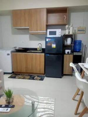 a kitchen with a black refrigerator and wooden cabinets at Coho Staycation with Free swimming in Las Pinas in Manila