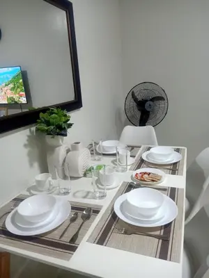 a dining room table with white plates and a fan at Coho Staycation with Free swimming in Las Pinas in Manila