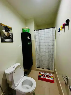 a bathroom with a toilet and a shower curtain at RoVi,s Nook SMDC Charm in Manila