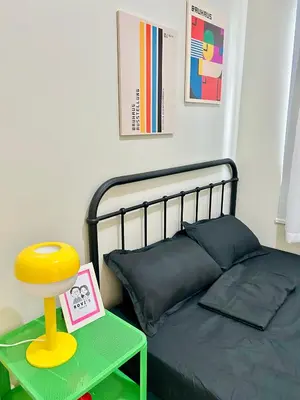 a bedroom with a bed and a table with a stool at RoVi,s Nook SMDC Charm in Manila