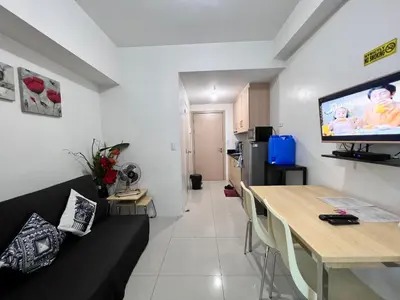 a living room with a couch and a television on the wall at Studio Units at SM Light Residences Condo Beside Boni MRT Station in Manila