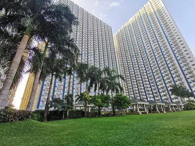 two tall buildings with palm trees in front of a park at Studio Units at SM Light Residences Condo Beside Boni MRT Station in Manila