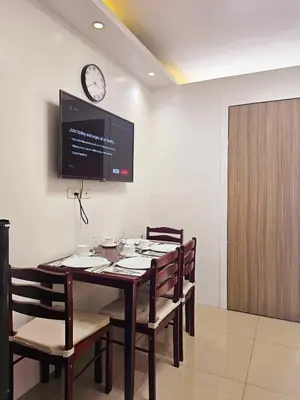 a dining room with a table and a clock on the wall at Hannah's Crib at Shore Residences with Balcony and Pool View in Manila