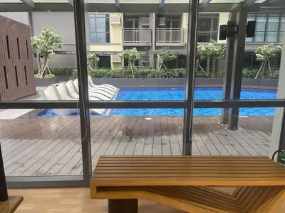 a view of a pool through a window with a bench at Lovely 2br near Airport, Solaire, & Okada - 6pax in Manila