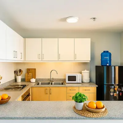 a kitchen with white cabinets and a microwave and oranges on a counter at Rare 3BR Modern Penthouse in BGC II Sleeps 12pax in Manila
