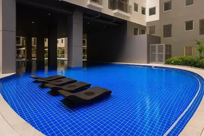 a swimming pool with lounge chairs in a building at Stylish & Cozy 1 bedroom near Mall of Asia in Manila