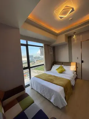 a bedroom with a bed and a large window at Lovely 2 bedroom near Airport & Okada in Manila