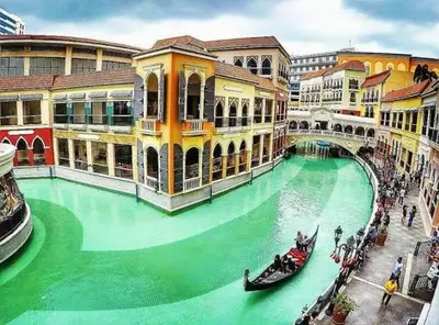 a green water canal with gondolas in a city at Morgan Suite a6 BGC shortwalk Venice Canal Mall in Manila