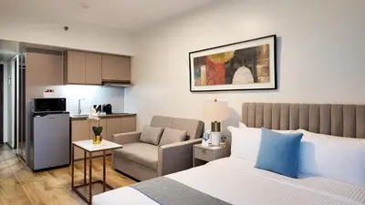 a bedroom with a bed and a chair and a kitchen at Savea Bay City Manila in Manila