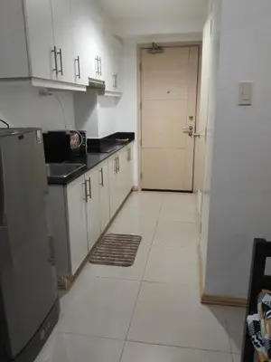 a kitchen with white cabinets and a door and a tile floor at MOA Sea Residences Condotel in Manila