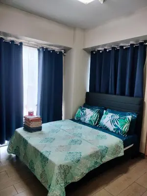 a bedroom with a bed with blue drapes at Rqui Family Room Pasay City in Manila
