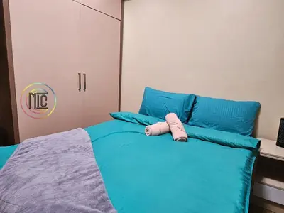 a bed with blue pillows and a pink object on it at Cozy 2BR UnitN Free Pool Gym with Karaoke Netflix in Manila