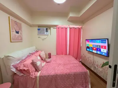 a bedroom with a pink bed and a flat screen tv at Boogsh Coquette Vibes Staycation In Pasig! in Manila