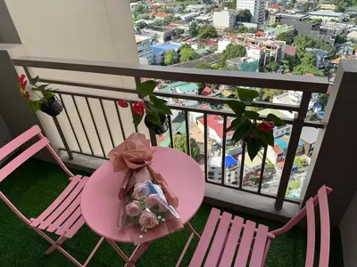 a pink table and chairs on a balcony with a view at Boogsh Coquette Vibes Staycation In Pasig! in Manila