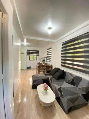 a living room with a black couch and a table at Cabuhat Duco Lodge 31 in Tanza