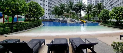 a swimming pool with chairs and a fountain in a city at All I Want-Relax at Shore Residences in MOA Complex in Manila