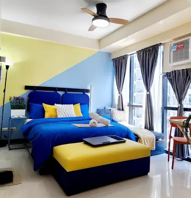 a blue and yellow bedroom with a bed and a ceiling at 14e BGC Unit 3 mins Walk to The Venice Grand Canal Mall Pet Friendly in Manila