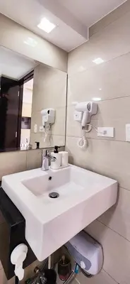 a bathroom with a white sink and a mirror at 2 Unique Side-by-Side Studios Vibrant & Zen at Viceroy BGC in Manila
