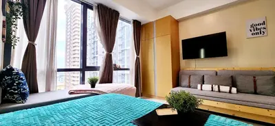 a bedroom with a bed and a tv and a window at 2 Unique Side-by-Side Studios Vibrant & Zen at Viceroy BGC in Manila