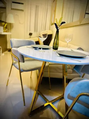 a white table with two plates and wine glasses at Addison Place at SMDC Charm in Manila