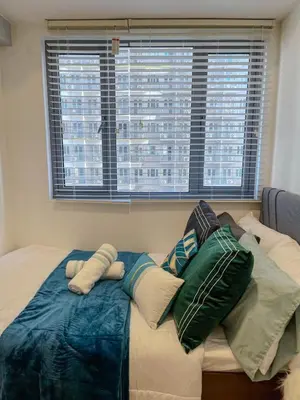 a bed with pillows on it in a room with a window at Rejuvenate at Fame Residences Mandaluyong SM MegaMall in Manila