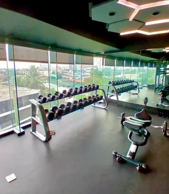 a gym with rows of dumbbells and a large window at 1BR in Makati Prime Location in Manila