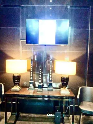 a table with two lamps and a tv on a wall at 1BR in Makati Prime Location in Manila