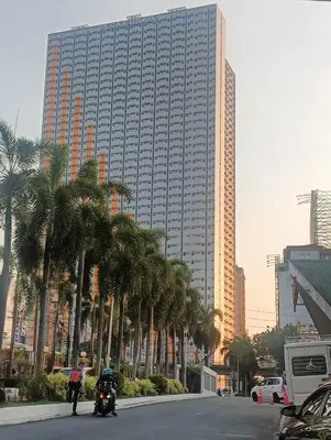 a street with palm trees in front of a tall building at Deca Cubao Tower Budget Condo by Ashti in Manila