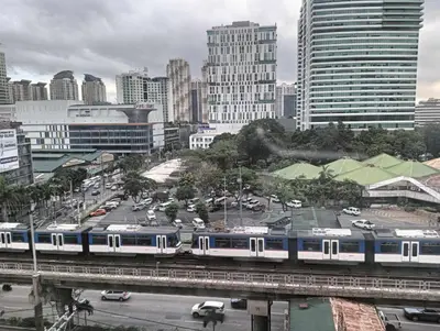 a blue and white train on a bridge in a city at Deca Cubao Tower Budget Condo by Ashti in Manila