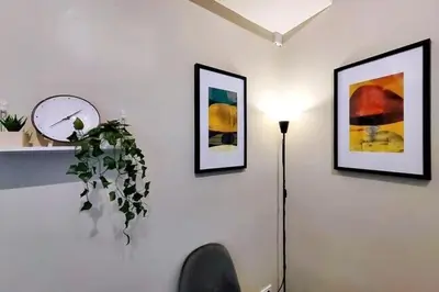 a white wall with three pictures and a clock and a lamp at 1BR Condotel Suite at Sunshine100 City Plaza #SS01-1 in Manila