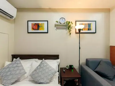 a living room with a couch and a clock on the wall at 1BR Condotel Suite at Sunshine100 City Plaza #SS02-1 in Manila