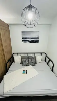 a bedroom with a large white bed with a chandelier at Affordable Stay in MOA in Manila