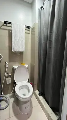 a bathroom with a toilet and a shower curtain at Affordable Stay in MOA in Manila