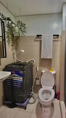 a bathroom with a white toilet and a sink at Affordable Stay in MOA in Manila