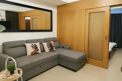 a living room with a couch and a mirror at Very Spacious Condo at Mall of Asia in Manila