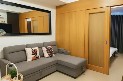 a living room with a couch and a mirror at Very Spacious Condo at Mall of Asia in Manila