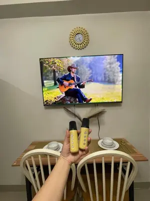 a person holding up two bottles on a table with a tv at Myras aesthetic unit in Manila