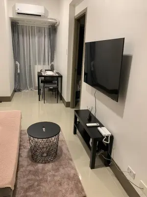 a living room with a couch and a table and a television at Fame Tower 2 Luxury Queen with own Washer in Manila