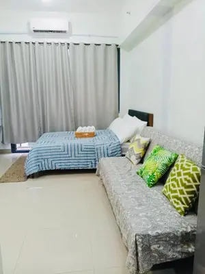 a bedroom with a couch with pillows on it at S Suite Home MOA Staycation in Manila